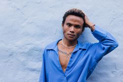 Asian male in blue shirt running hand through his hair while looking at camera