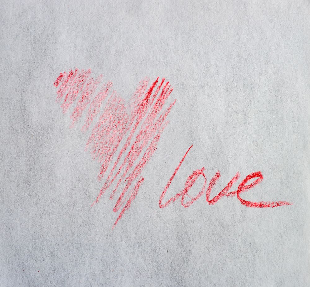 Valentine Day holiday card concept with red heart and love scribbled on paper