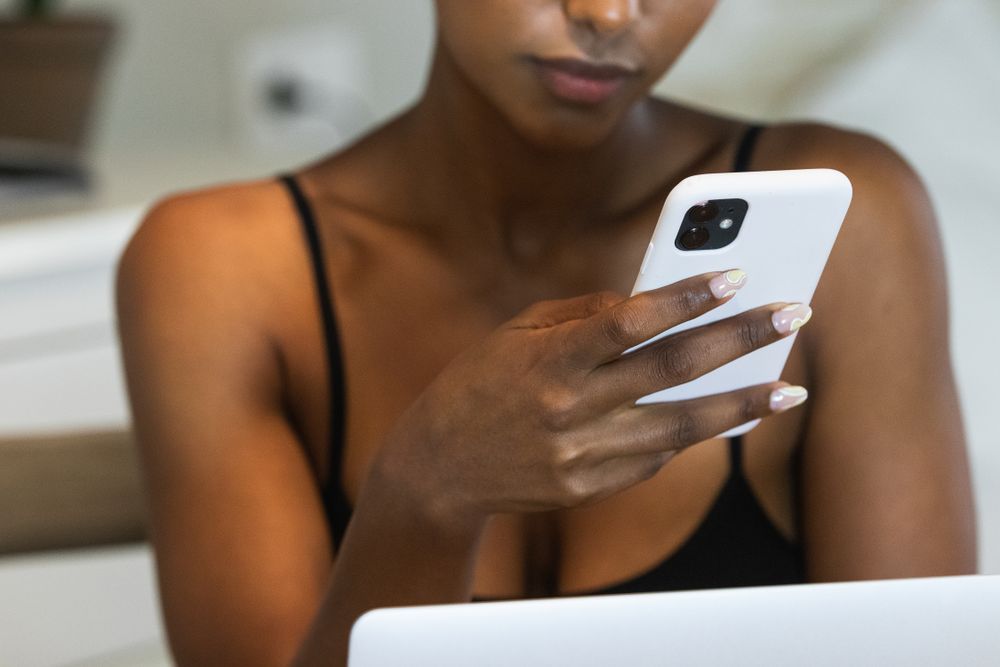 Anonymous Black woman using smartphone while sitting on chair