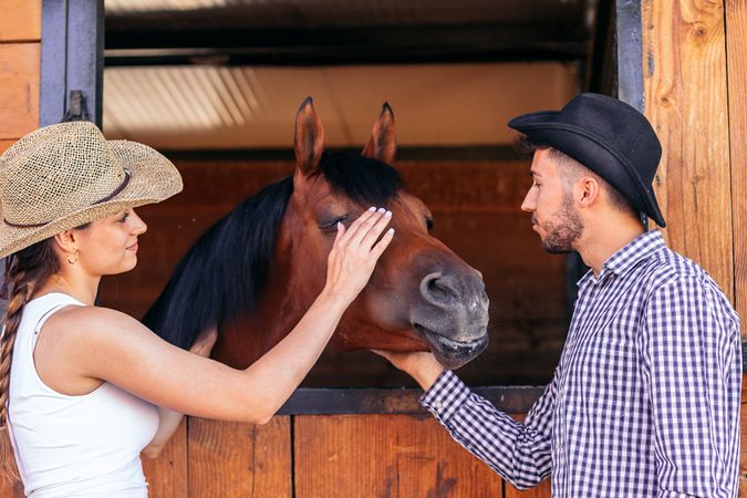 Two people taking care of a horse in the stable