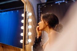 brunette female in peignoir applying makeup