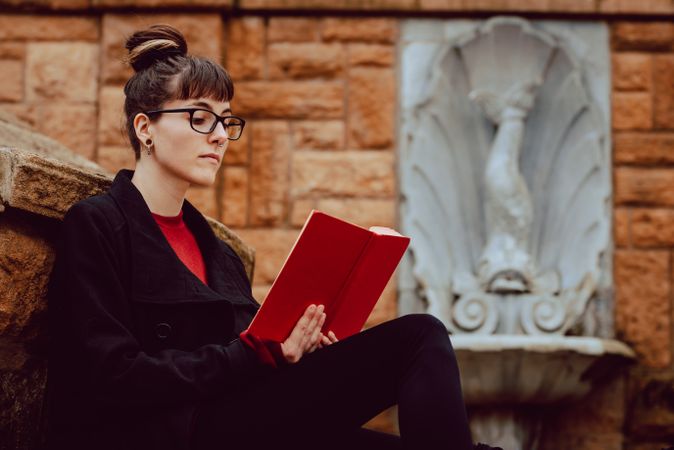 Young woman reading book on steps