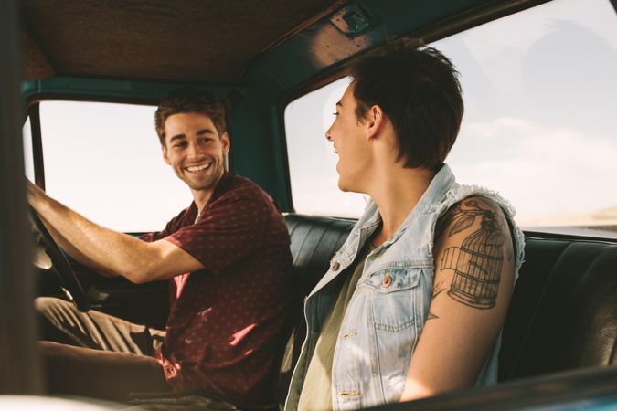Cheerful young couple enjoying road trip ride in vintage truck