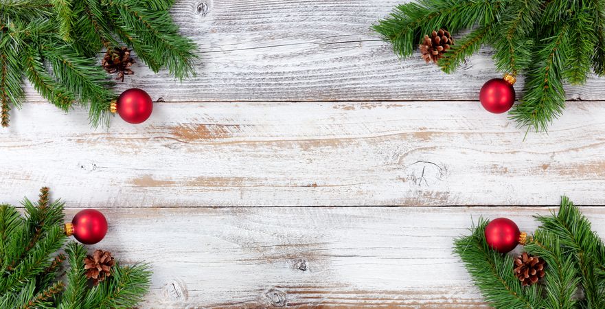 Christmas Evergreen branches and red ball decorations in all corners on vintage wooden boards