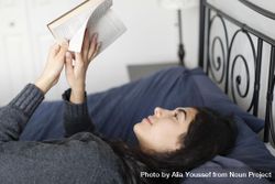 Content young woman laying in bed reading a book 56kDV4