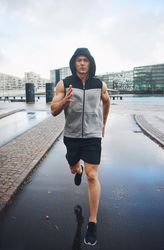 Muscular man running outside on overcast cast, vertical