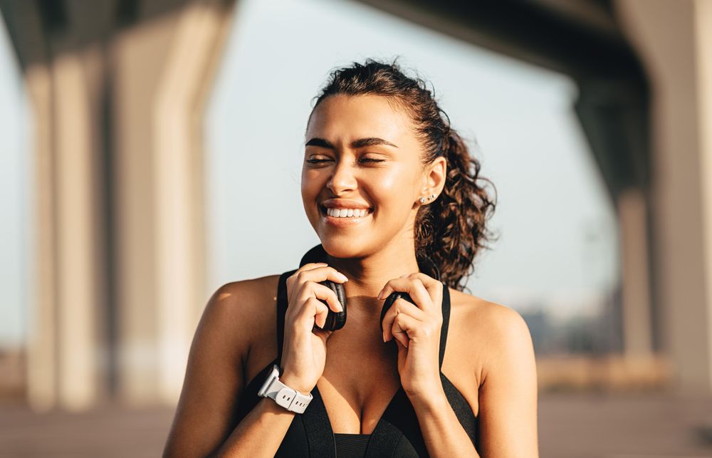 Woman smiling with her eyes closed and headphones around her neck