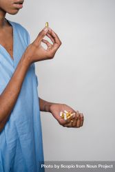 Cropped image of Black woman taking medicine against light background 5QX8g0