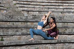Instructor helping woman doing yoga in low lunge pose