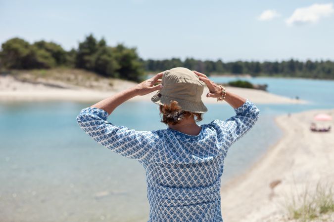Woman in hat standing against seascape in sunlight