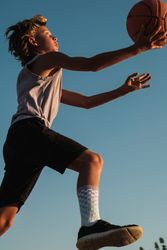 Active boy throwing basketball in hoop