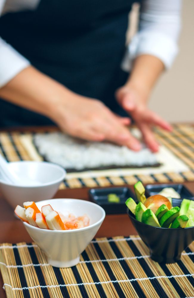 Avocado, cucumber and crab meat bowl with chef preparing sushi in background