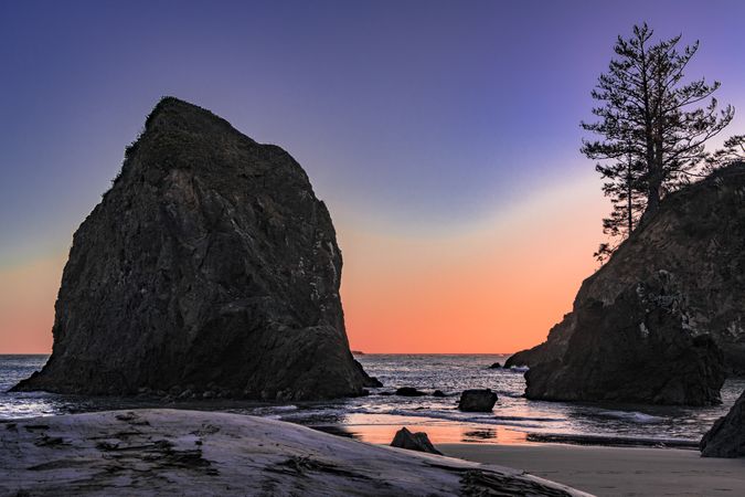 Large rock on the coast at dusk with beautiful purple orange sky