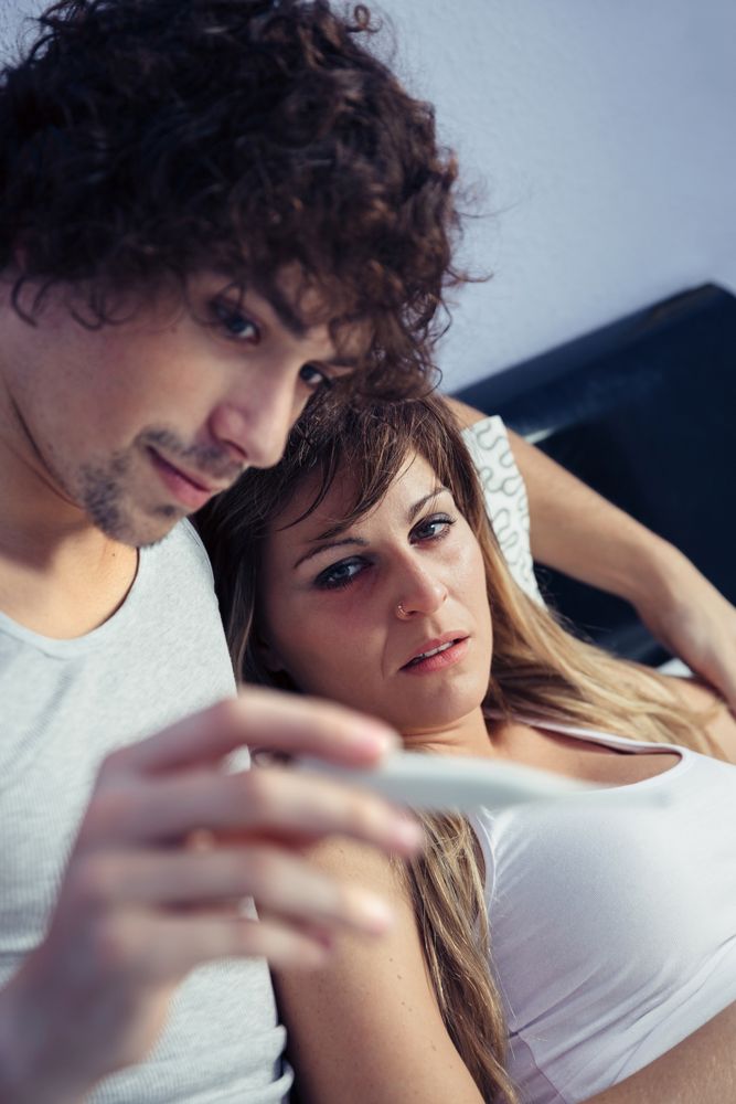 Man showing temperature of sick woman on thermometer