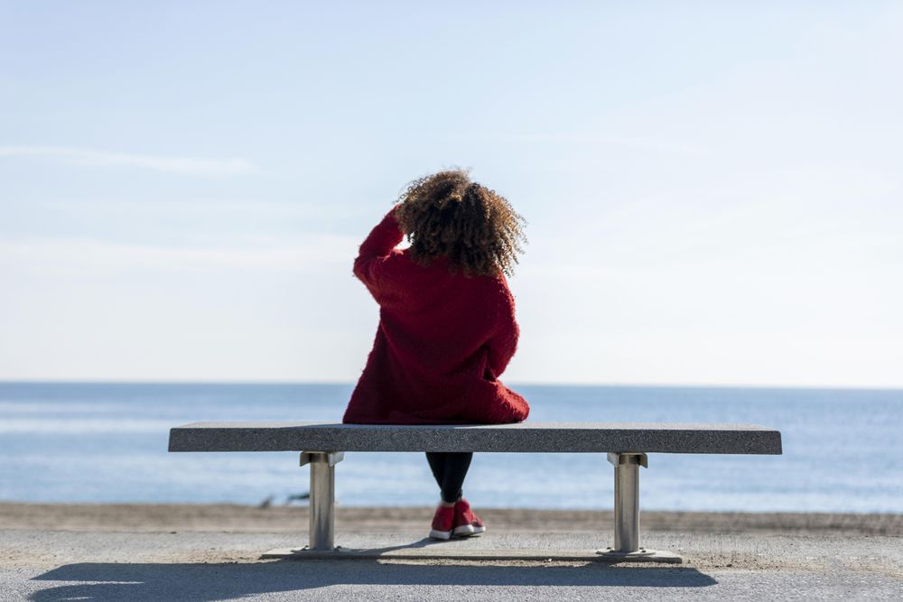 Back of woman enjoying view on seat overlooking the ocean