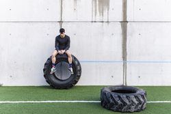 Man sitting on heavy tire on lawn