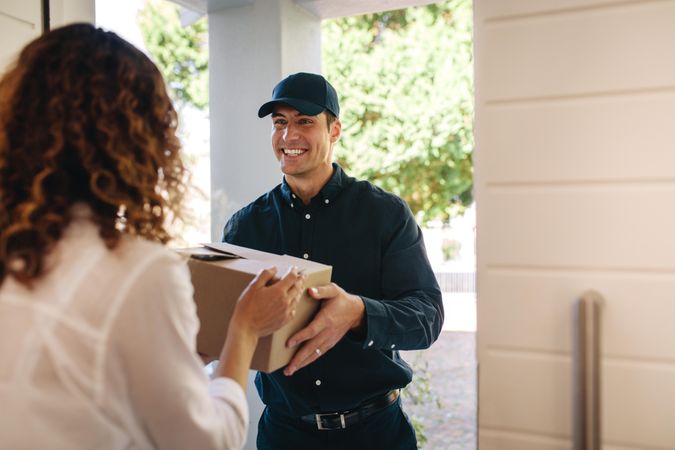 Smiling delivery man handing over a box to female at home
