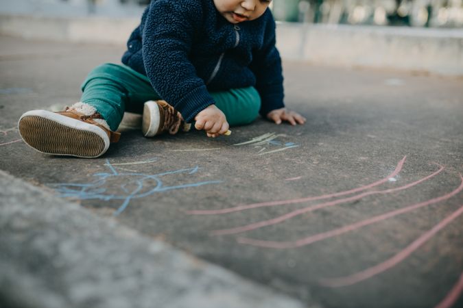 A toddler playing with chalk