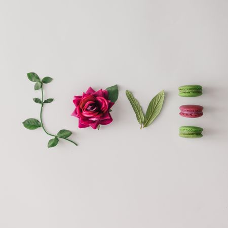 Word LOVE made out of flower, leaves and macarons