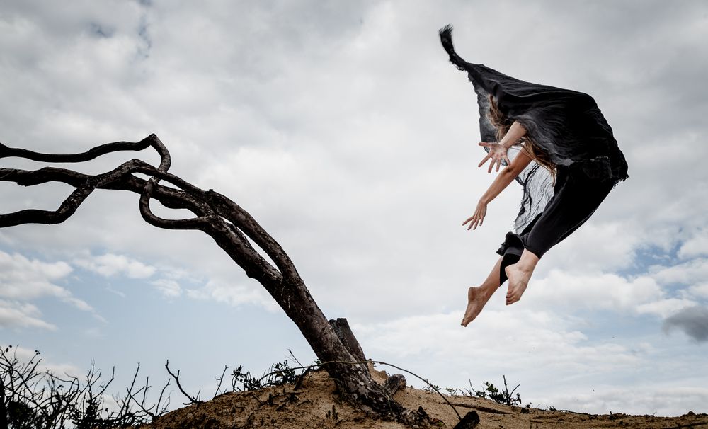 Woman posing in air near dry twigs and blue sky