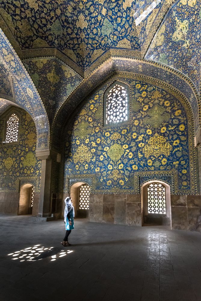 Woman standing in mosque with colorful tiles on dome