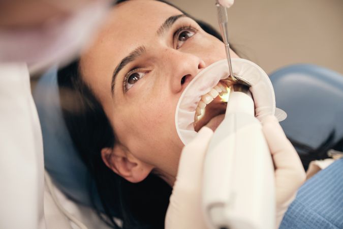 Crop dentist with 3D scanner serving female client