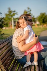 Baby girl standing on a bench hugging to woman