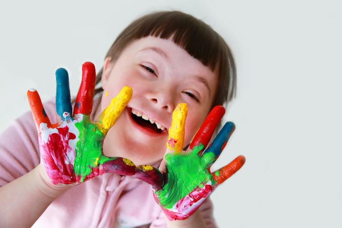 Top view of young girl holding her painted hands out to camera
