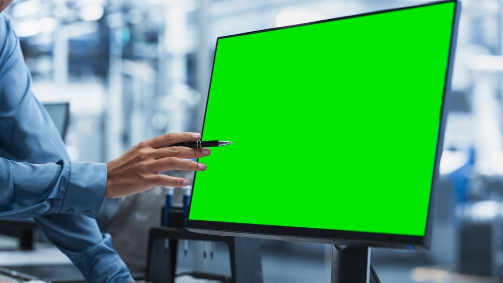Close Up On Green Screen Of Desktop Computer With Chromakey On Display at a Modern Factory With Robotic Arms.