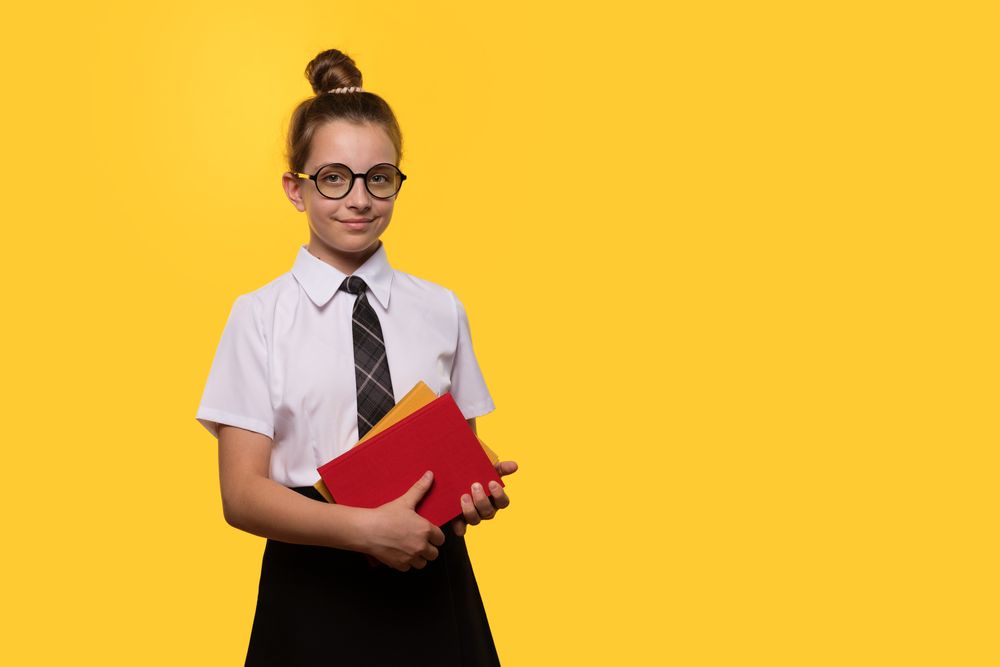 Teen girl holding books, wearing glasses and school uniform
