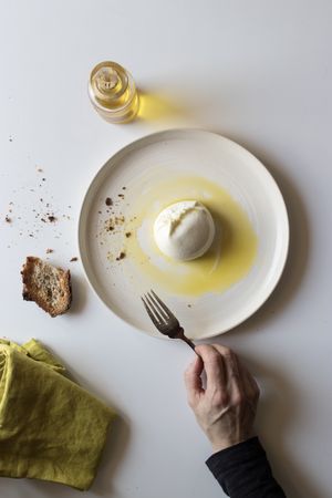 Crop hand taking cheese near bread and oil