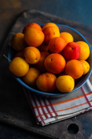 Bowl of orange plums on wooden counter
