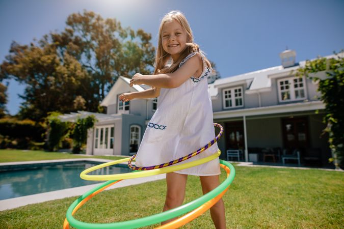 Beautiful little girl having fun with hula hoops outdoors