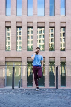 Bearded man leaning outside talking on mobile phone