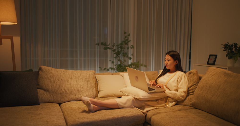 Inspired South Korean Freelance Journalist Relaxing on a Cozy Couch While Working