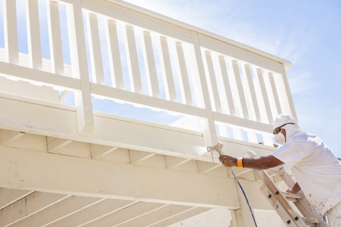 House Painter Spray Painting A Deck of A Home