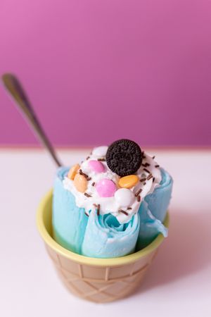 Close up of a blue rolled ice cream decorated with chocolates, cream and a cookie