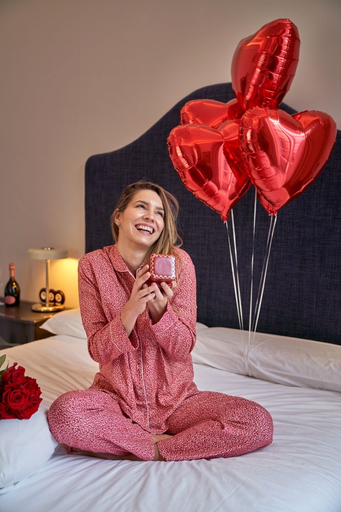 Dreamy woman with gifts on Saint Valentine day on bed