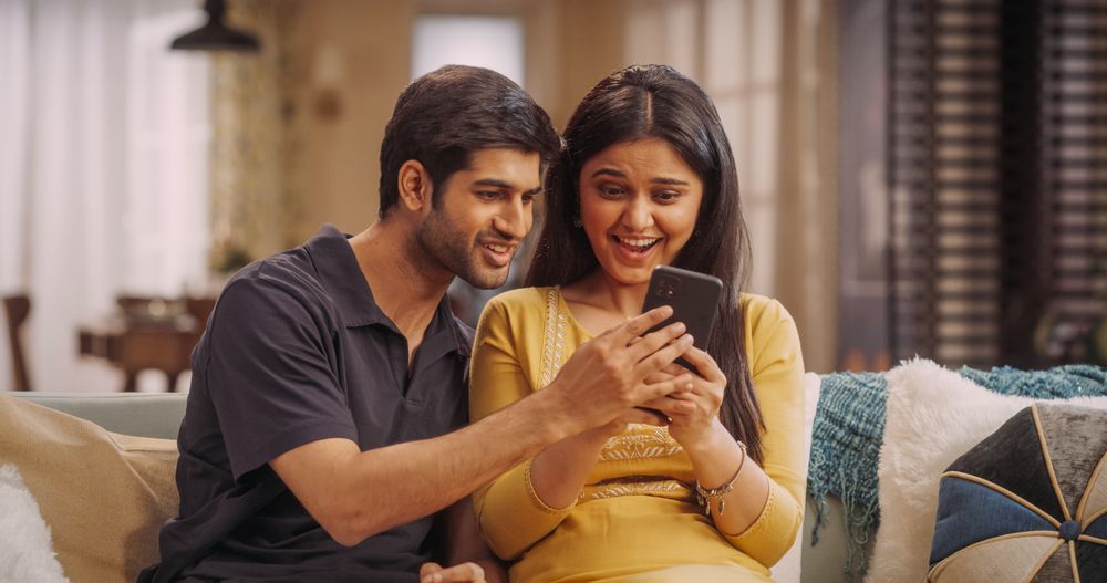 Indian Couple Engaged In Online Shopping, Scrolling Through Product Listings And Hunting For Bargains.