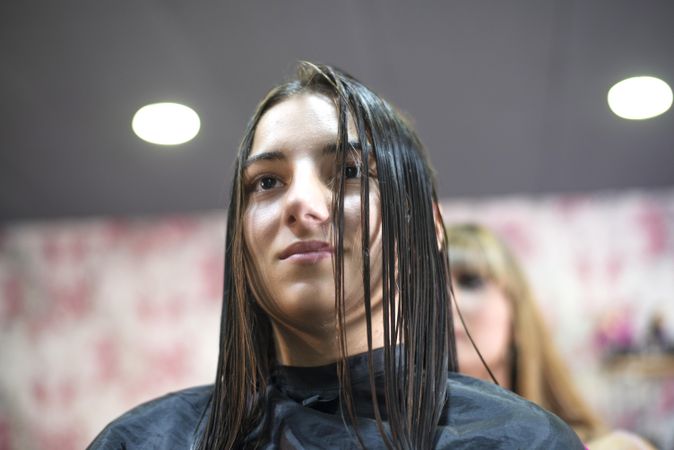 Brunette teenager with wet brunette hair sitting having a hair cut