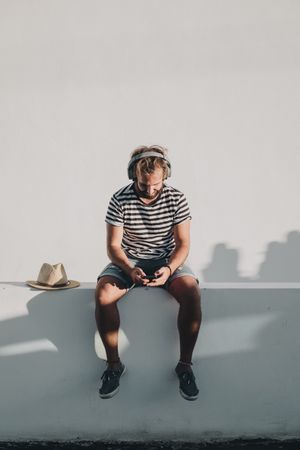 Young male sitting with smartphone and headphones