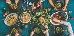 Group of people serving themselves food at festive table with candy canes and roasted pears