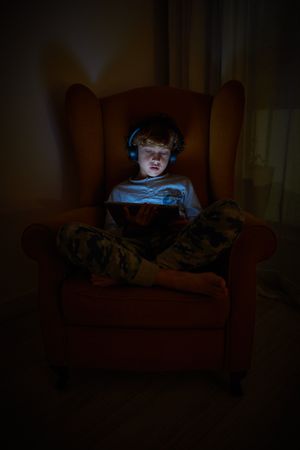 Curious boy playing on tablet in darkness