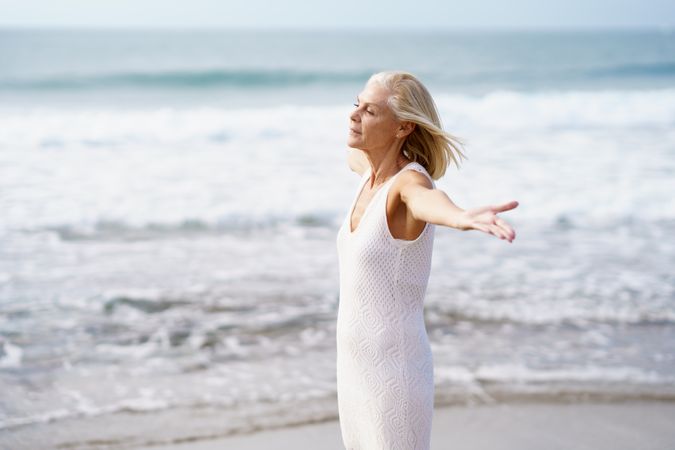 Side view of mature woman with outstretched arms on a beautiful beach