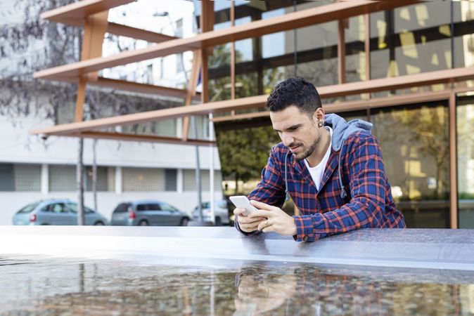 Man with smartphone by city fountain