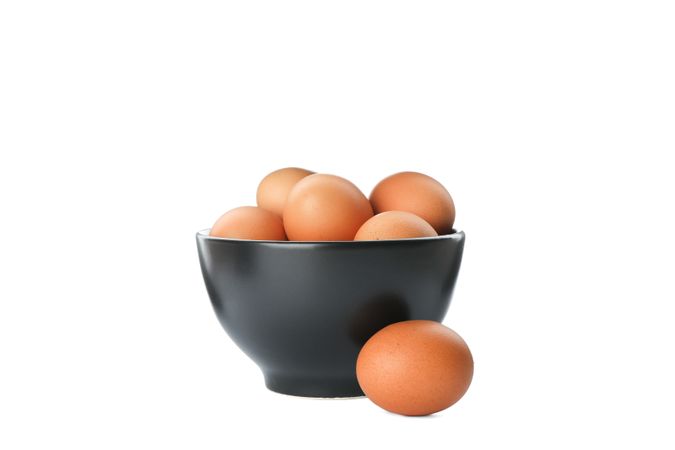 Few raw chicken eggs in bowl on plain background