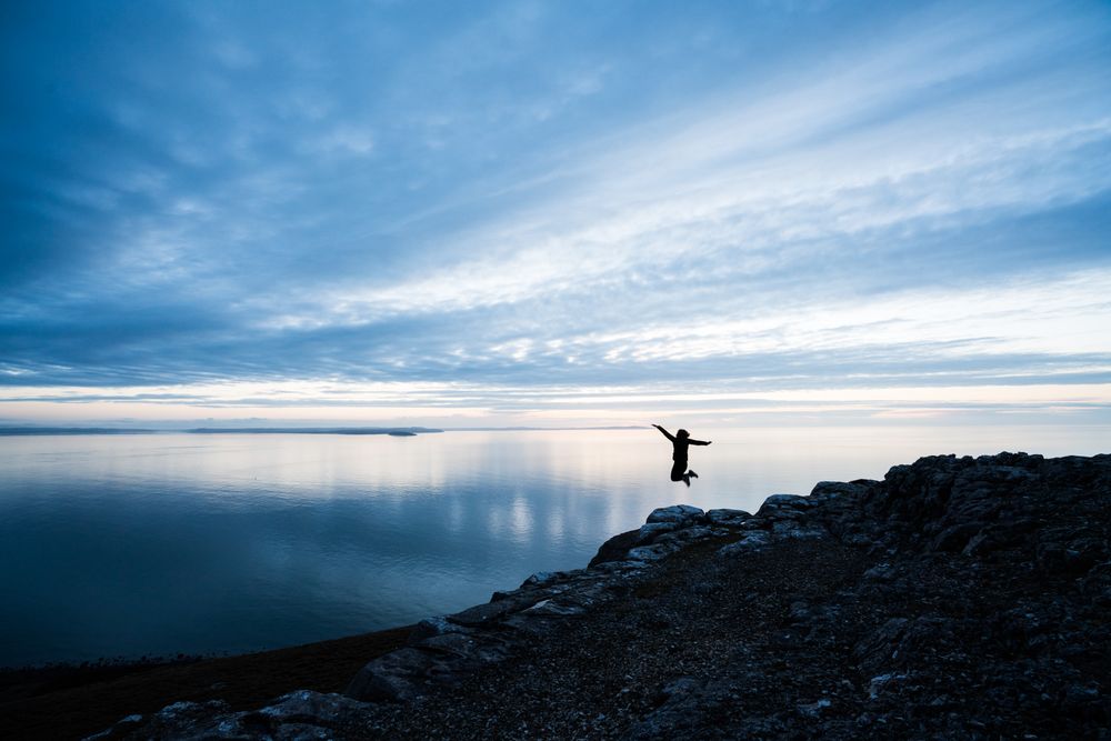 Happy man jumping on rocky coastline