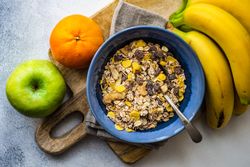 Top view of hearty bowl of oatmeal surrounded by fresh fruits