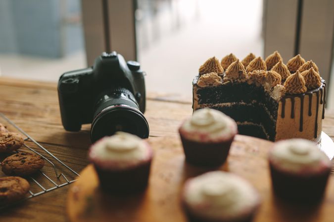 Dslr camera sitting on wooden table with desserts