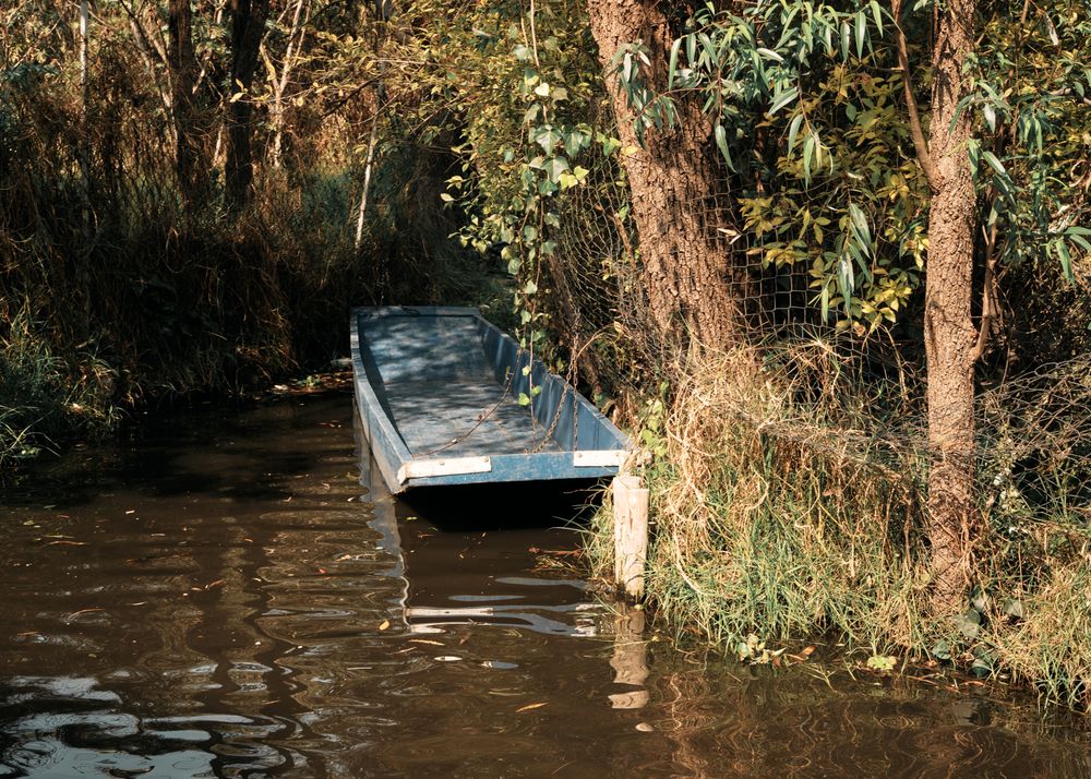 Small blue boat along riverbank
